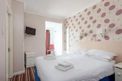 a bedroom with a white bed with towels on it at Barrowfield Hotel in Newquay