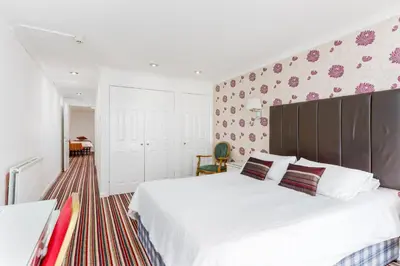 a bedroom with a large white bed with a large headboard at Barrowfield Hotel in Newquay