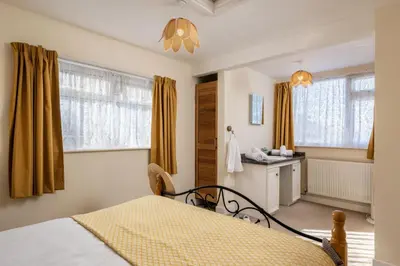 a bedroom with a bed and a sink and windows at Casa Sirena Apartment in Fistral, Newquay in Newquay