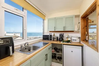 a kitchen with a sink and a large window at Casa Sirena Apartment in Fistral, Newquay in Newquay