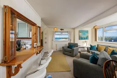 a kitchen and living room with a couch and chairs at Casa Sirena Apartment in Fistral, Newquay in Newquay