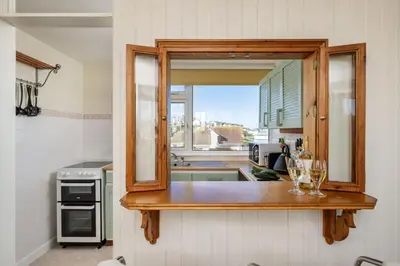 a kitchen with a mirror and glasses on a counter at Casa Sirena Apartment in Fistral, Newquay in Newquay