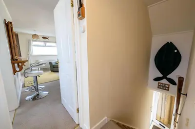 a hallway with a room with a chair and an office at Casa Sirena Apartment in Fistral, Newquay in Newquay