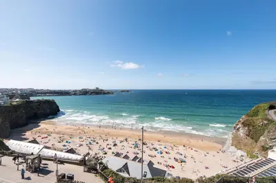 a beach with a crowd of people and the ocean at Casa Sirena Apartment in Fistral, Newquay in Newquay