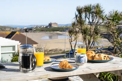 a wooden table with plates of food and orange juice at Casa Sirena Apartment in Fistral, Newquay in Newquay