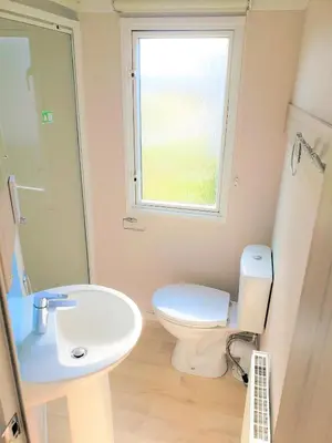 a bathroom with a toilet and a sink and a window at Sea Break, Perran Sands, Perranporth in Perranporth