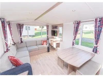 a caravan living room with a table and a couch at Sea Break, Perran Sands, Perranporth in Perranporth