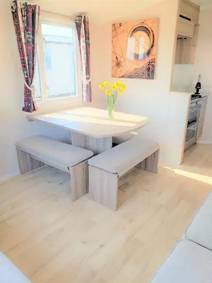 a kitchen with a table and benches and a window at Sea Break, Perran Sands, Perranporth in Perranporth