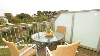 a table with a bowl of fruit on a balcony at Chymoresk - Self Catering Holiday Cottage Hayle St Ives Bay in Hayle