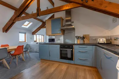 a kitchen with blue cabinets and a dining room at Sunset View in Bude