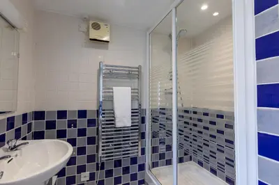 a blue and white bathroom with a sink and a shower at Sunset View in Bude