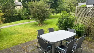 a table and chairs in a yard with a garden at Creek Cottage in Budock Water