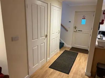a hallway with two white doors and a rug at Creek Cottage in Budock Water