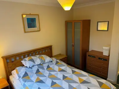 a bedroom with a large bed and a dresser at Creek Cottage in Budock Water