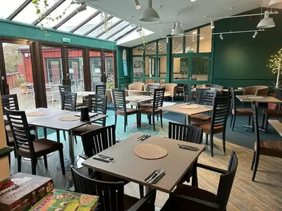 a dining room with tables and chairs and windows at Creek Cottage in Budock Water