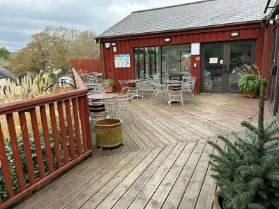 a wooden deck with tables and chairs on a building at Creek Cottage in Budock Water