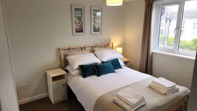 a bedroom with a bed with white sheets and blue pillows at Top Location Perranporth Apartment in Perranporth