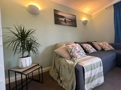 a living room with a couch and a potted plant at Top Location Perranporth Apartment in Perranporth