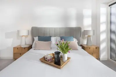a white bed with a tray with flowers on it at Sunny Eco Home minutes from the beach (Tamsin) in Newquay