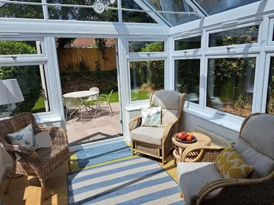 a screened in porch with chairs and a table at Trevallion in Saint Endellion