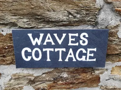 a sign that says waves confidence on a stone wall at Waves Cottage, Newquay. in Newquay