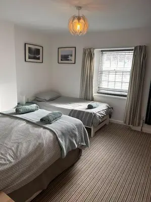 a bedroom with two beds and a window at Waves Cottage, Newquay. in Newquay