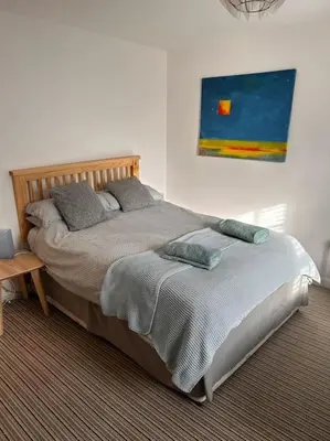 a bed in a bedroom with a painting on the wall at Waves Cottage, Newquay. in Newquay