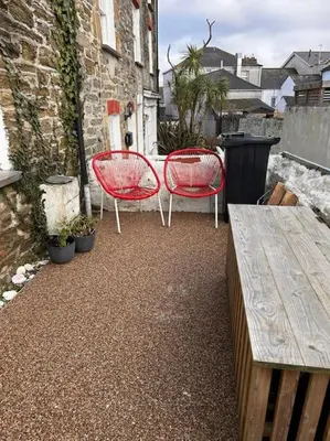 two red chairs and a table on a patio at Waves Cottage, Newquay. in Newquay