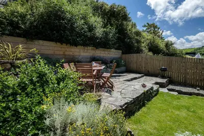 a patio with a table and chairs in a garden at Sea Horses in Port Isaac