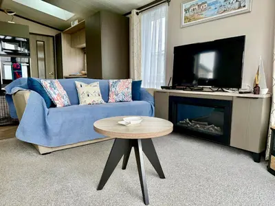 a living room with a blue couch and a tv at Holywell Lodge in Newquay