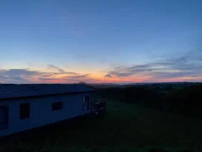 a house on a hill with a sunset in the background at Holywell Lodge in Newquay