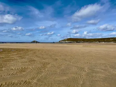 an empty beach with footprints in the sand at Holywell Lodge in Newquay