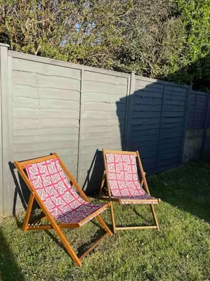 two chairs sitting in the grass next to a fence at Peaceful centrally located, 2 Bedroom Bungalow. in Camborne