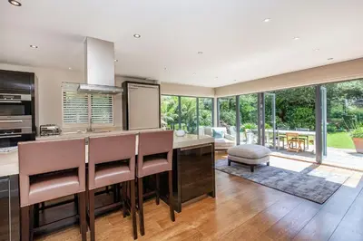 a kitchen with a large island with leather chairs at Moonfleet in Saint Mawes
