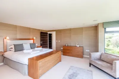a bedroom with a large bed and a chair at Moonfleet in Saint Mawes
