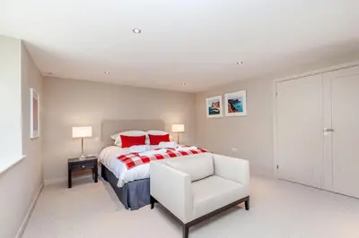 a bedroom with a bed and a white chair at Moonfleet in Saint Mawes