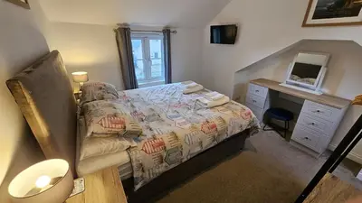 a bedroom with a bed with a dresser and a desk at Pepperpot in Portreath