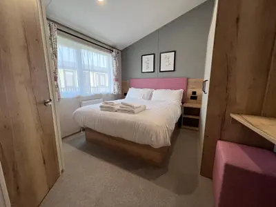 a bedroom with a large bed with a pink headboard at Holywell View 30 in Cubert