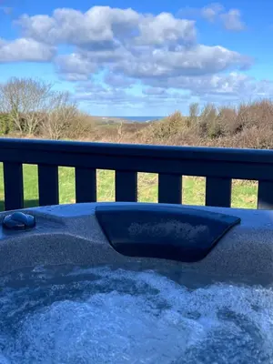 a hot tub on a balcony with a view of a field at Holywell View 30 in Cubert