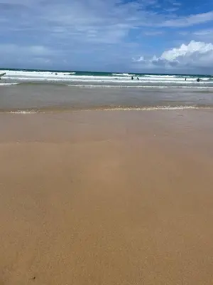 a sandy beach with people in the ocean at Holywell View 30 in Cubert