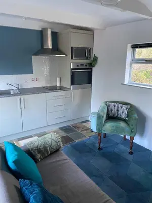 a kitchen with a couch and a chair in a room at Pond Cottage in Coverack