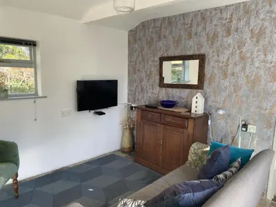 a living room with a couch and a flat screen tv at Pond Cottage in Coverack