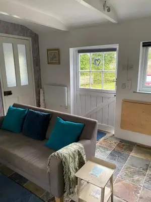 a living room with a couch and two windows at Pond Cottage in Coverack