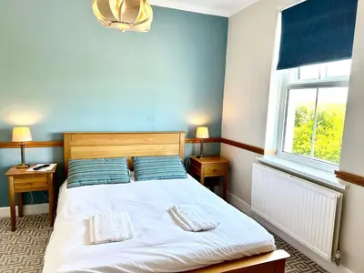 a bedroom with a bed with blue walls and a window at St George's Hotel in Perranporth