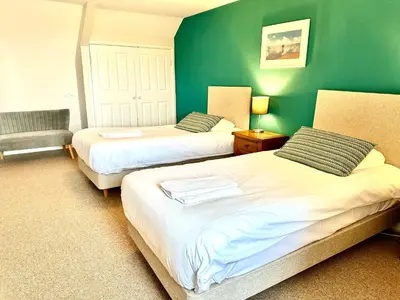 a bedroom with two beds and a green wall at St George's Hotel in Perranporth
