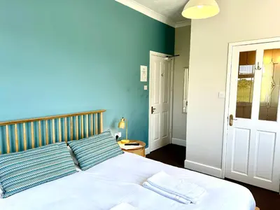 a bedroom with a white bed with a blue wall at St George's Hotel in Perranporth