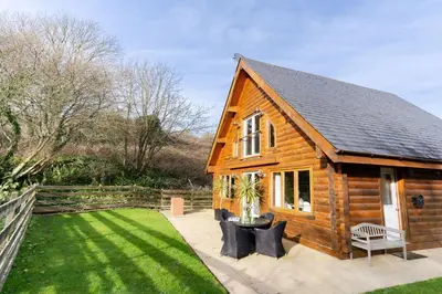 a small wooden house with a grass yard at Hillview in Little Petherick