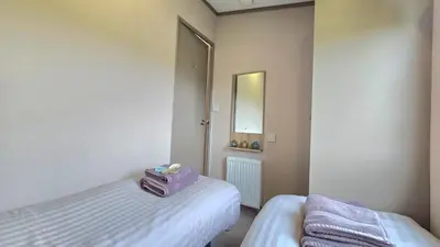 a small bedroom with two beds and a mirror at Perranporth HOT TUB 3 Bed Dog friendly Home in Newquay
