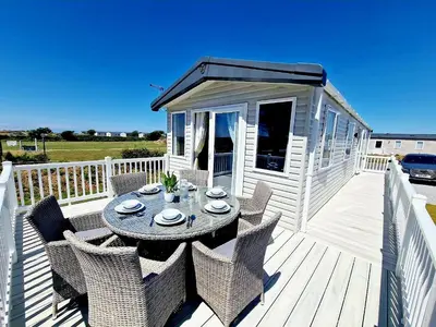 a table and chairs on a deck with a house at Perranporth HOT TUB 3 Bed Dog friendly Home in Newquay