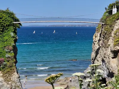 a bridge over the ocean with a beach and sailboats at Perranporth HOT TUB 3 Bed Dog friendly Home in Newquay
